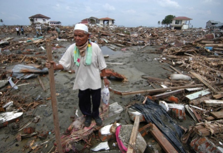 File photo of Acehnese man walking through debris left behind by last week's massive tsunami in the town of Banda Aceh